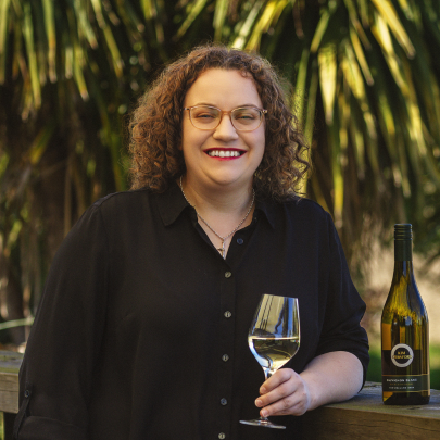 Woman with glass of wine and greenery in the background